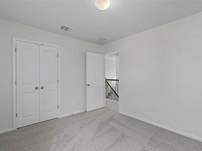A quiet secondary bedroom features plush carpet and ample closet storage, offering comfort and practicality.