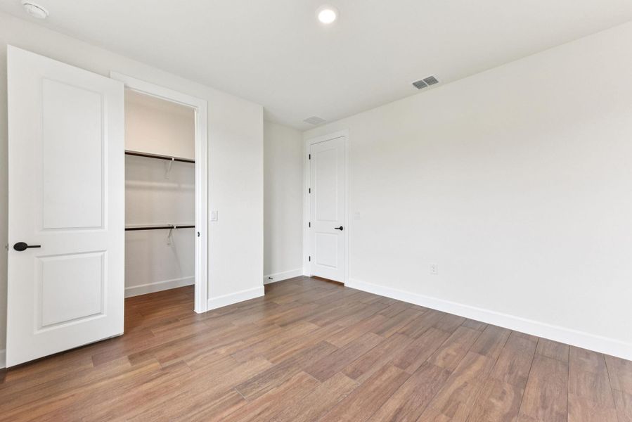 Unfurnished bedroom with a spacious closet, wood finished floors, and recessed lighting