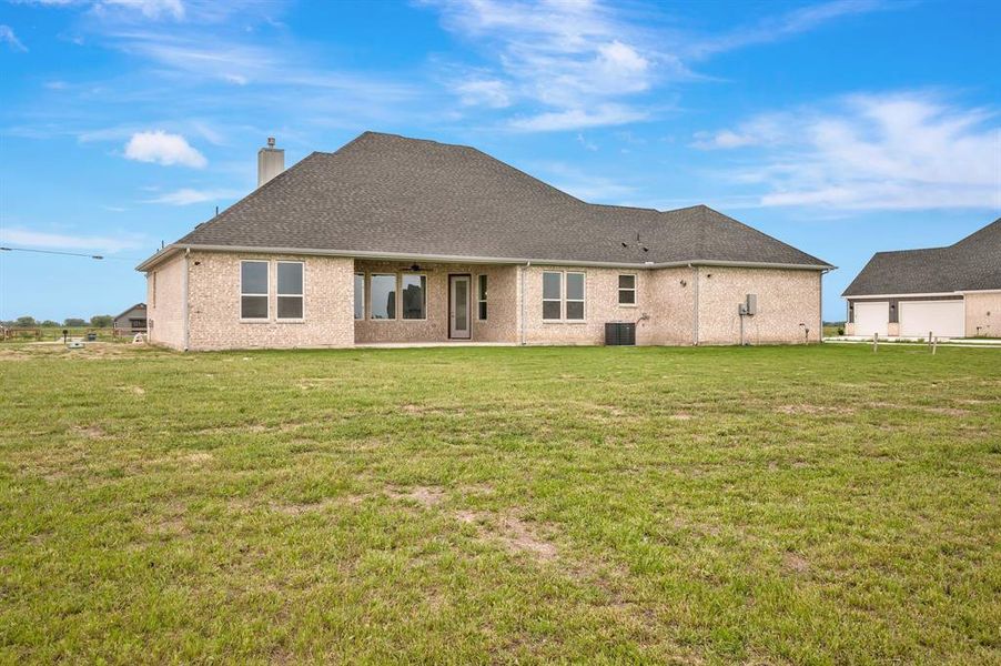 Rear view of property with a lawn, ceiling fan, central air condition unit, and a chimney Rear view of property with a lawn, ceiling fan, central air condition unit, and a chimney