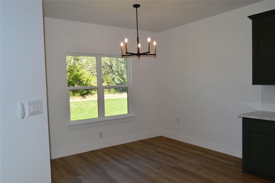 Unfurnished dining area featuring dark wood-style floors and a chandelier Unfurnished dining area featuring dark wood-style floors and a chandelier