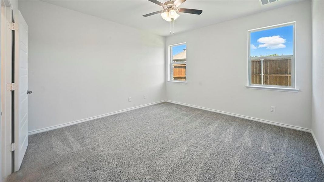 Carpeted spare room featuring baseboards and ceiling fan