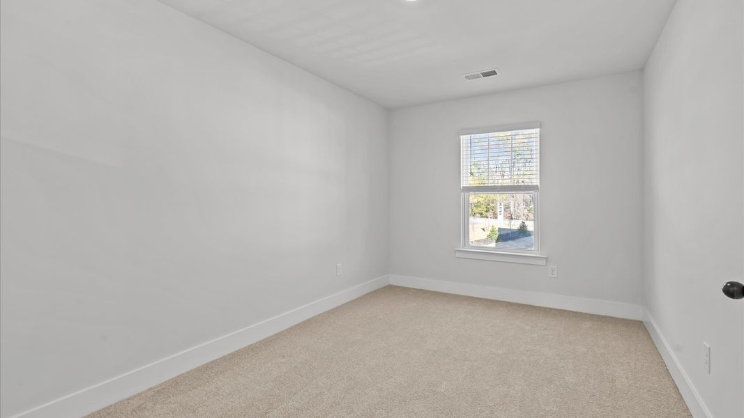 Highly functional bedroom with large windows, carpeted flooring, and tasteful finishes throughout