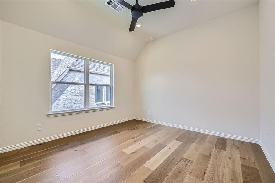 Secondary bedroom with ceiling fan, light hardwood / wood-style flooring, and vaulted ceiling