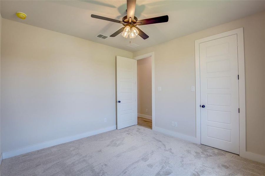 Unfurnished bedroom with ceiling fan and light colored carpet