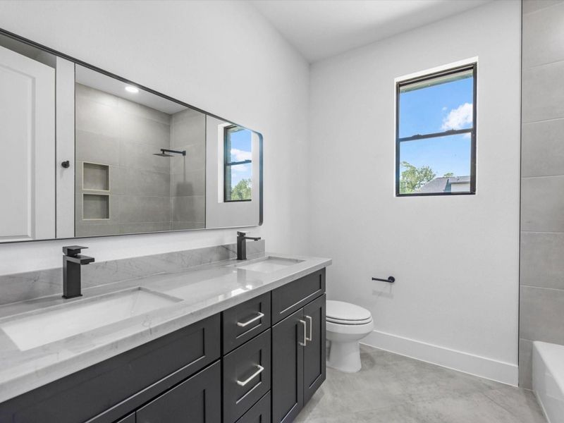 Guest Bathroom that is shared between the two secondary bedrooms. Featuring double sinks and sleek fixtures.