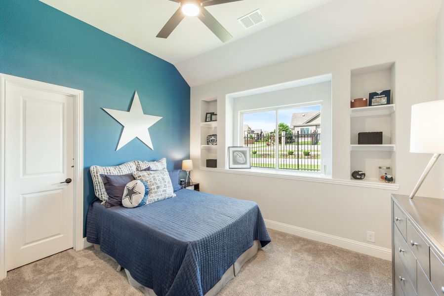 Bedroom with teal accent wall, star decor, blue bedding, built-in shelves, and ceiling fan Bedroom with teal accent wall, star decor, blue bedding, built-in shelves, and ceiling fan