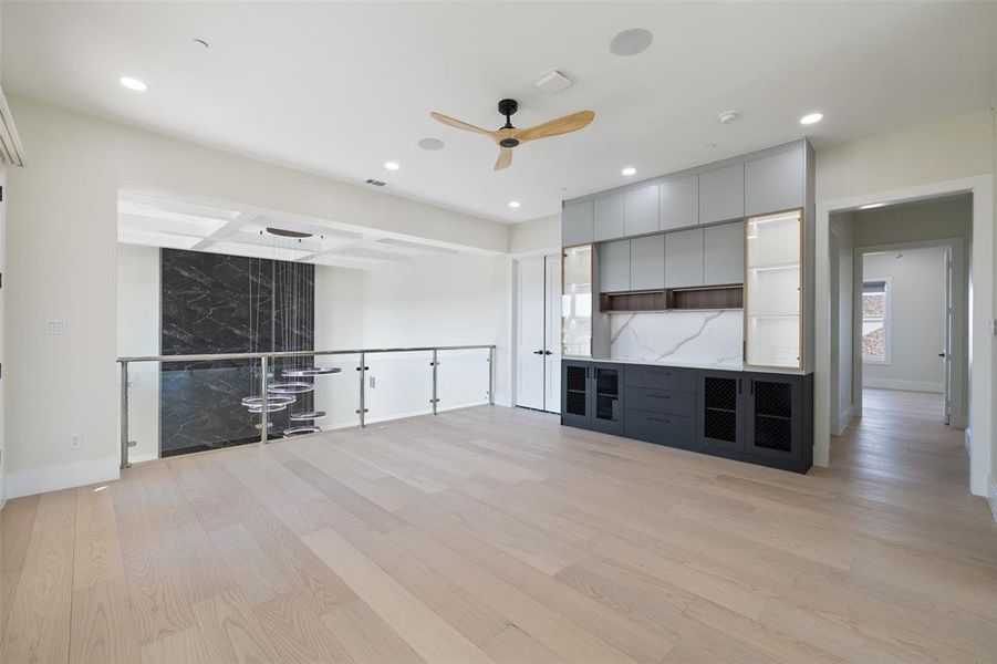 Unfurnished living room with beamed ceiling, light wood-type flooring, and ceiling fan