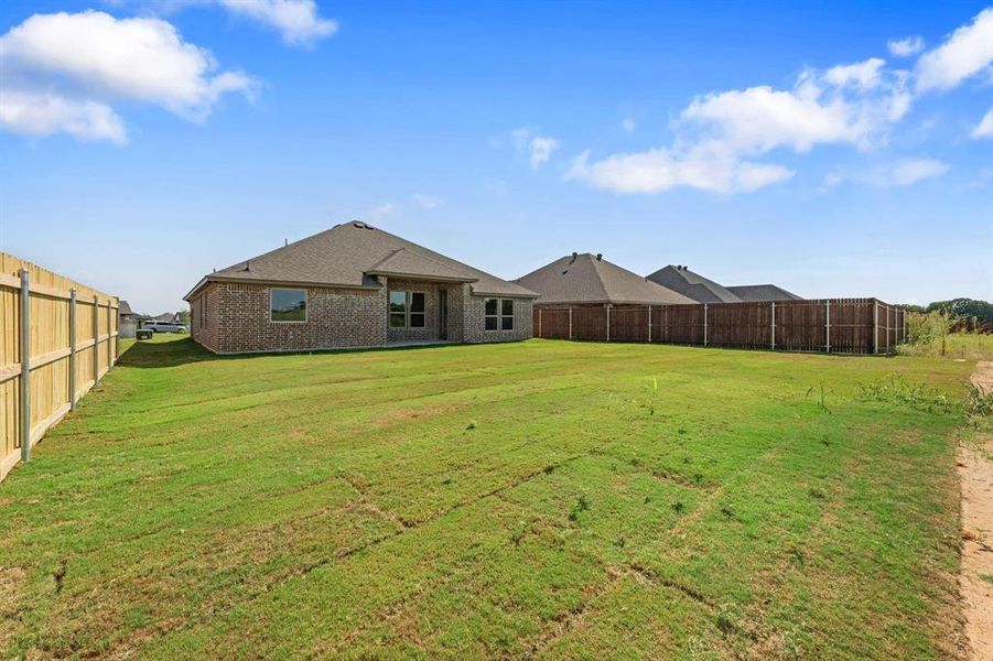 Back of house featuring brick siding, a fenced backyard, and a patio