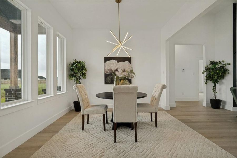 Dining area featuring wood-finish flooring, a contemporary chandelier, multiple vertical windows, and a wide cased opening Dining area featuring wood-finish flooring, a contemporary chandelier, multiple vertical windows, and a wide cased opening