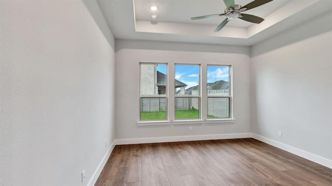 Empty room featuring hardwood / wood-style floors, ceiling fan, and a raised ceiling