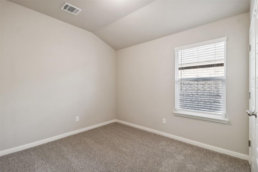 Spare room with carpet floors, vaulted ceiling, and baseboards Spare room with carpet floors, vaulted ceiling, and baseboards