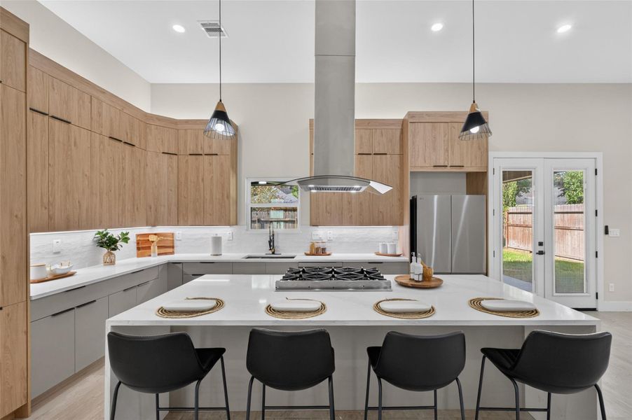 Spacious modern kitchen featuring sleek cabinetry, a large island with seating for four, stainless steel appliances, and elegant pendant lighting.
