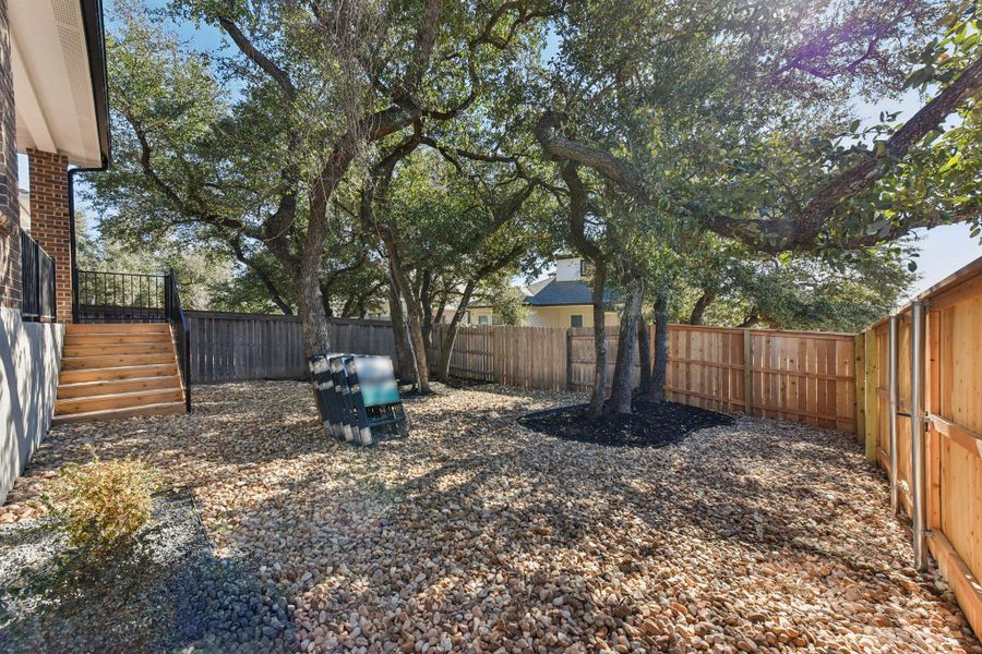 A private, gravel-covered yard offers shade from mature trees and new fencing. A private, gravel-covered yard offers shade from mature trees and new fencing.