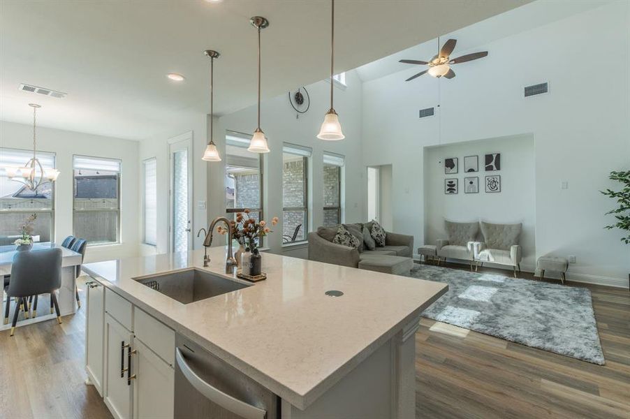 Open-concept living space featuring an island kitchen with stone countertops and pendant lighting, wood-finish flooring, a vaulted ceiling, and recessed lighting