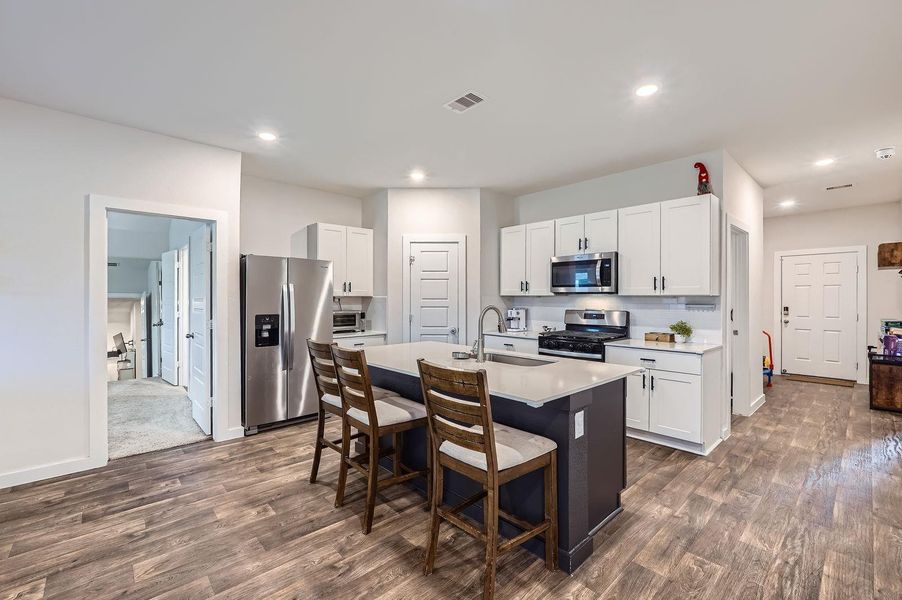 Kitchen featuring visible vents, a breakfast bar, light countertops, a sink, and stainless steel appliances