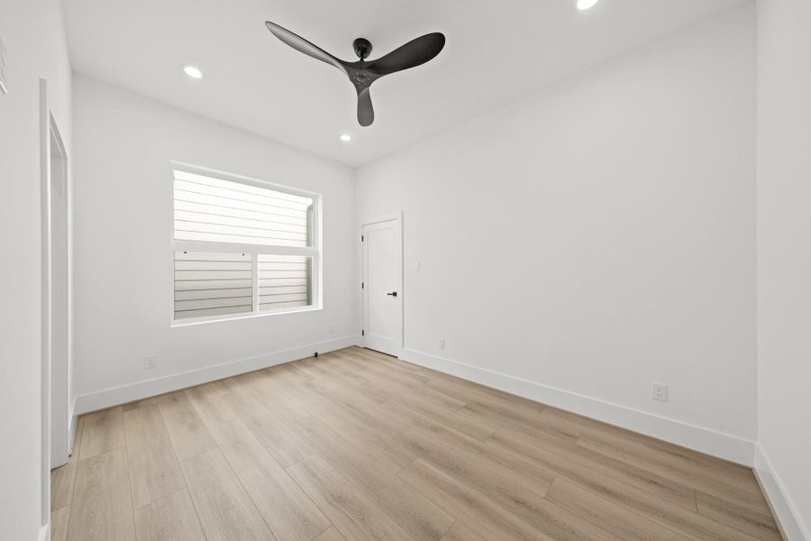The second bedroom has luxury vinyl floors, recessed lights, a large sliding window with a transom window above, a ceiling fan and a walk-in closet.