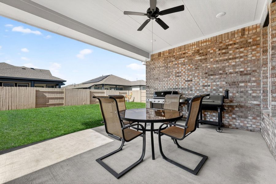 Covered patio with a gas stub for your BBQ. Fenced backyard with a patio, a ceiling fan, outdoor dining space.