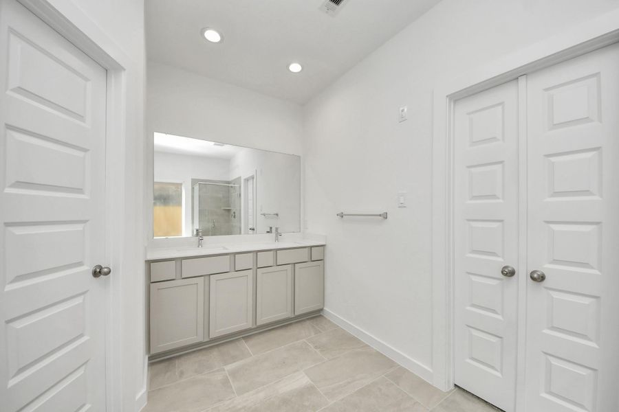 Elevate your daily routine at the elegant vanity, now equipped with double sinks, light countertops, modern hardware, and beautiful recessed lights. Sample photo of completed home with similar floor plan. Actual colors and selections may vary.