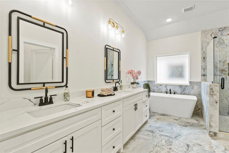 Full bath featuring a marble finish shower, tile walls, a freestanding bath, double vanity, and a wainscoted wall Full bath featuring a marble finish shower, tile walls, a freestanding bath, double vanity, and a wainscoted wall