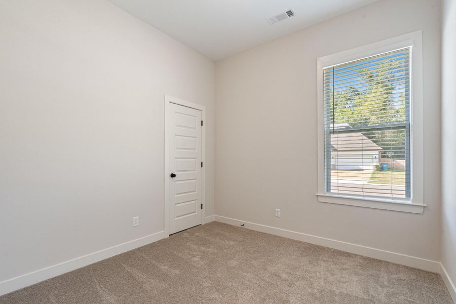 Neutral wall tones, carpet flooring, a multi-pane window with blinds, and a paneled door with dark hardware Neutral wall tones, carpet flooring, a multi-pane window with blinds, and a paneled door with dark hardware