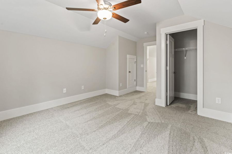 Unfurnished bedroom featuring lofted ceiling, light carpet, and a ceiling fan