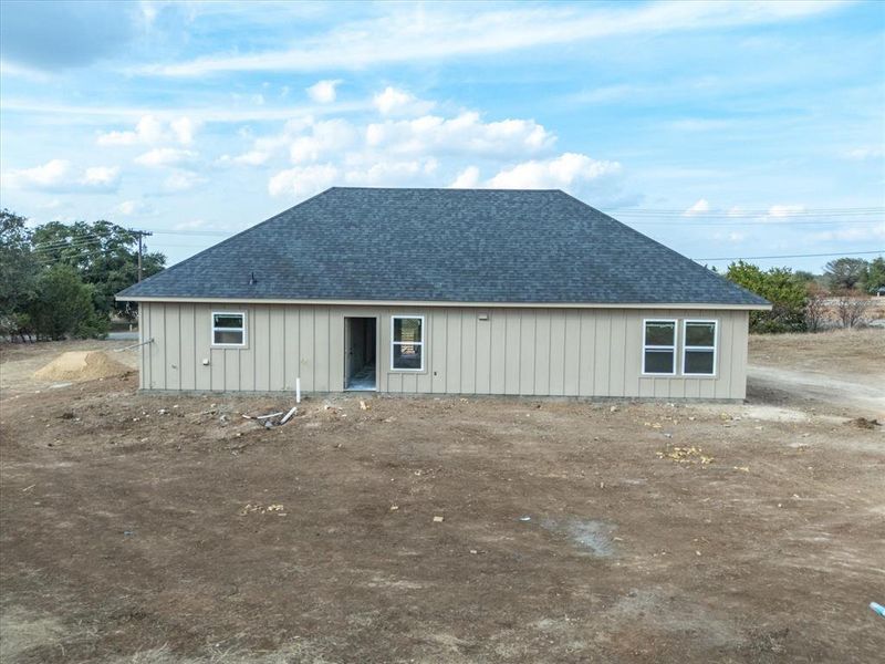 Rear view of house with roof with shingles and board and batten siding