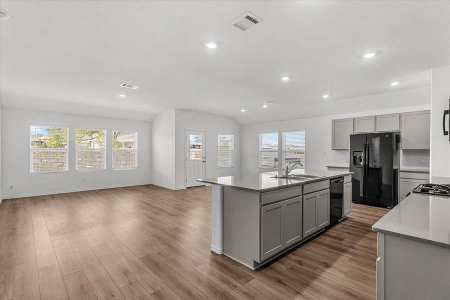 Kitchen featuring black appliances, a kitchen island with sink, dark wood-style flooring, recessed lighting, and gray cabinetry