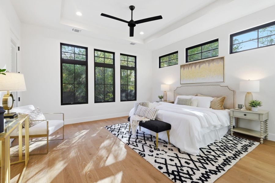 Bedroom with a raised ceiling, light wood-type flooring, a ceiling fan, and recessed lighting