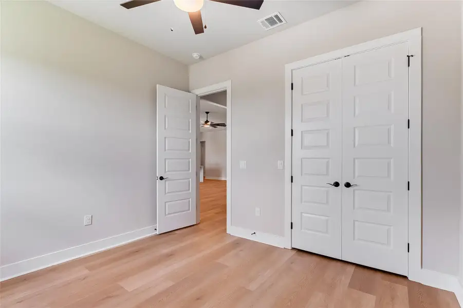 Unfurnished bedroom featuring light wood-style flooring, ceiling fan, and a closet