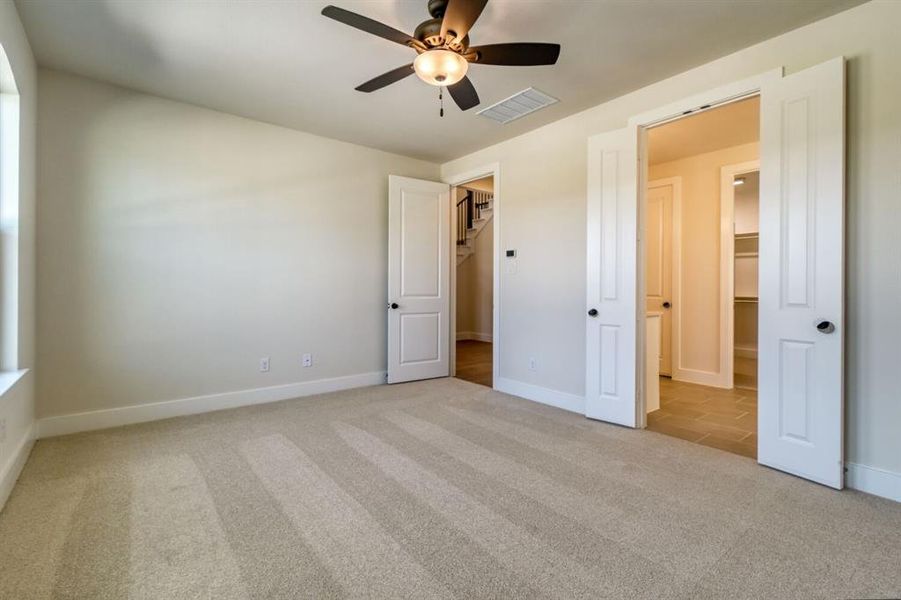 Unfurnished bedroom with light carpet, ceiling fan, and a spacious closet Unfurnished bedroom with light carpet, ceiling fan, and a spacious closet
