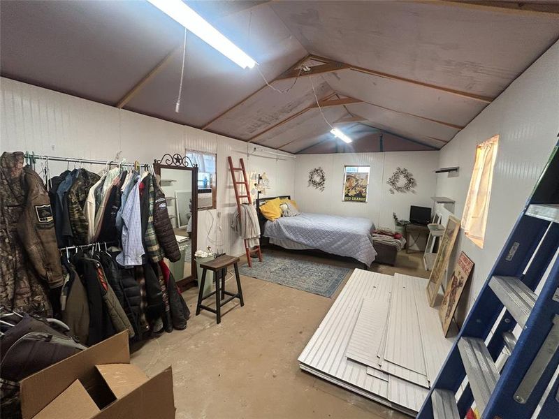Bedroom featuring concrete flooring, lofted ceiling, and multiple windows Bedroom featuring concrete flooring, lofted ceiling, and multiple windows