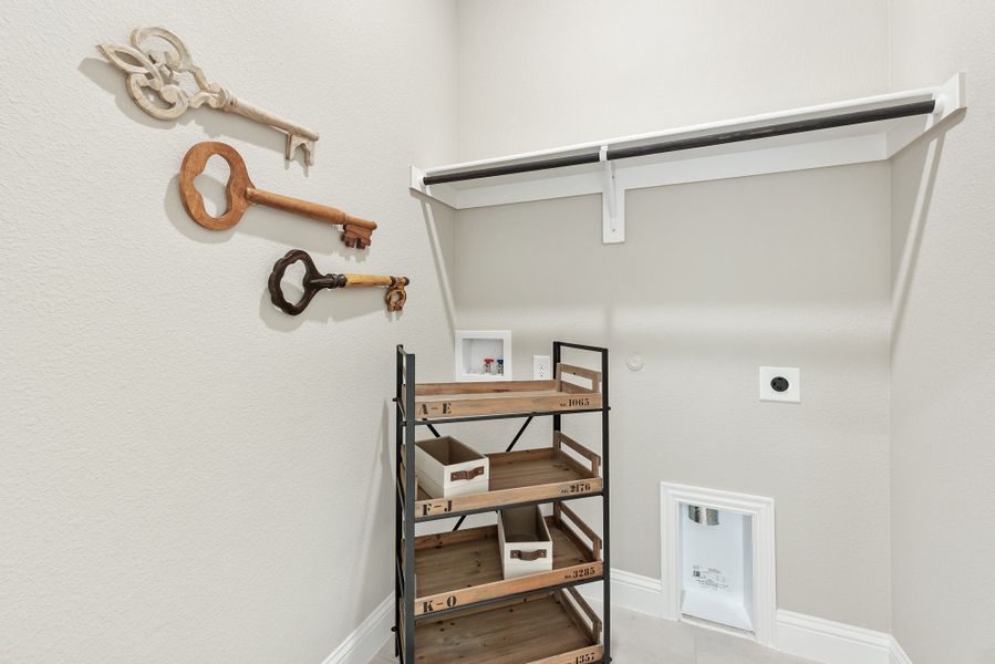 Closet or utility room with wall-mounted clothing rod, wooden shelving unit, and decorative oversized key wall art Closet or utility room with wall-mounted clothing rod, wooden shelving unit, and decorative oversized key wall art
