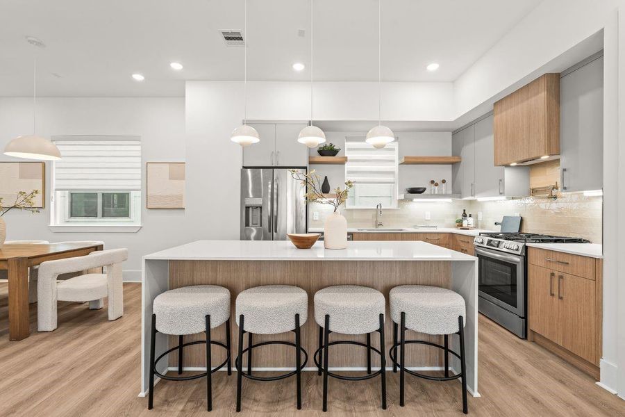 Centered around a substantial waterfall island, the kitchen pairs warm wood tones with clean architectural lines, establishing a natural focal point for gathering, entertaining, and daily ritual.