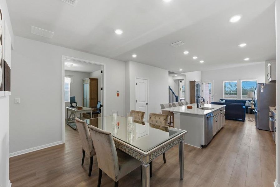 Dining area with light wood finished floors and recessed lighting