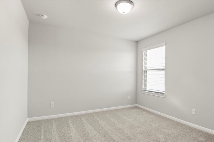 Empty room featuring light colored carpet, baseboards, and a smoke detector