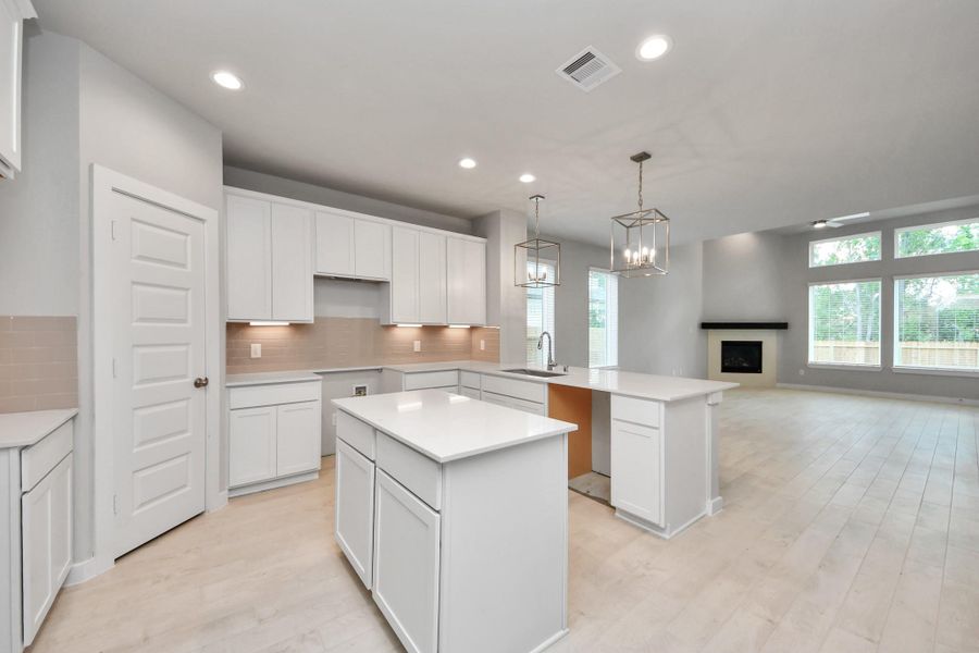 This kitchen is truly a chef's dream! This haven Boasts high ceilings, recessed & pendant lighting, stained wood cabinets, granite countertops, stainless steel appliances, a modern tile backsplash.  All of this overlooks your expansive family room, creating a perfect space for culinary delights and family gatherings.