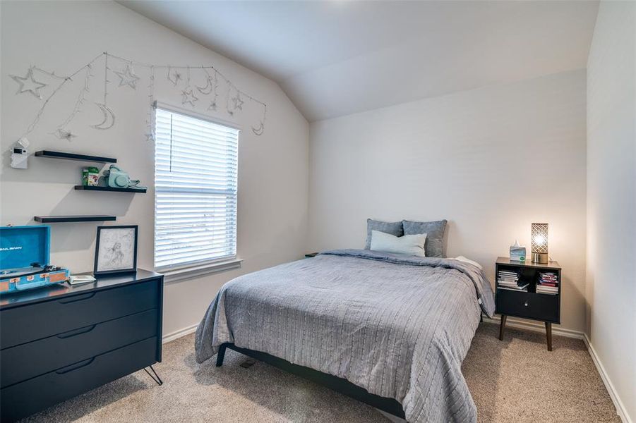 Bedroom with lofted ceiling, light colored carpet, and baseboards