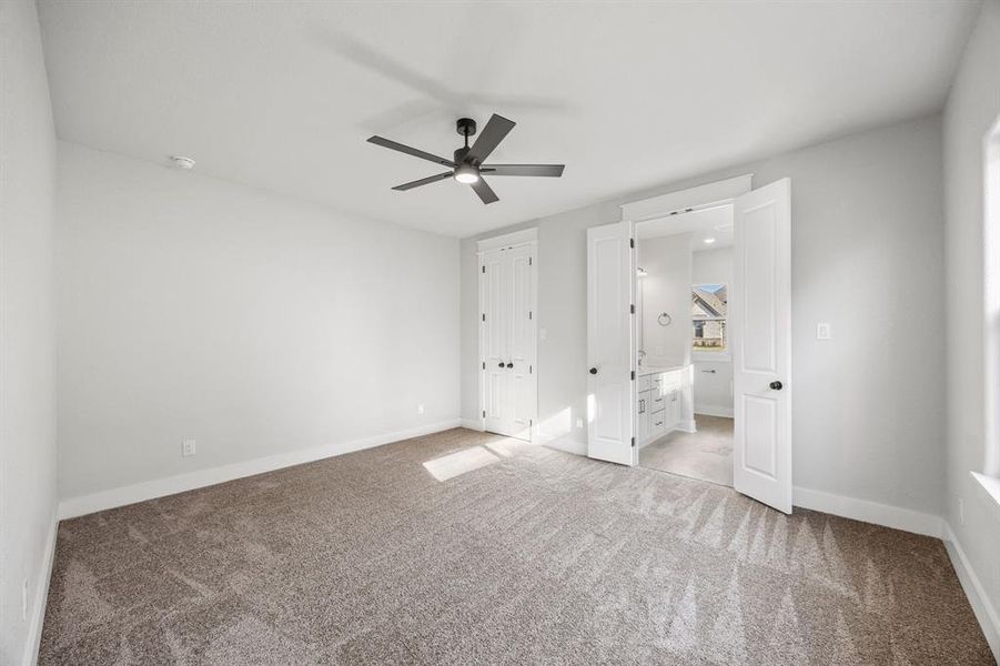 Unfurnished bedroom featuring ensuite bath, carpet flooring, a ceiling fan, and a closet