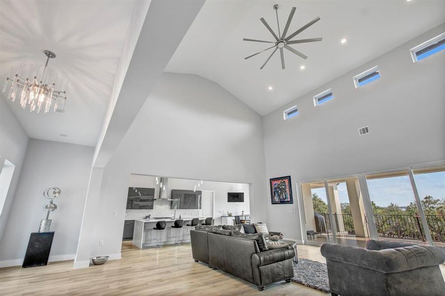 Living room with recessed lighting, light wood-style flooring, a chandelier, high vaulted ceiling, and french doors