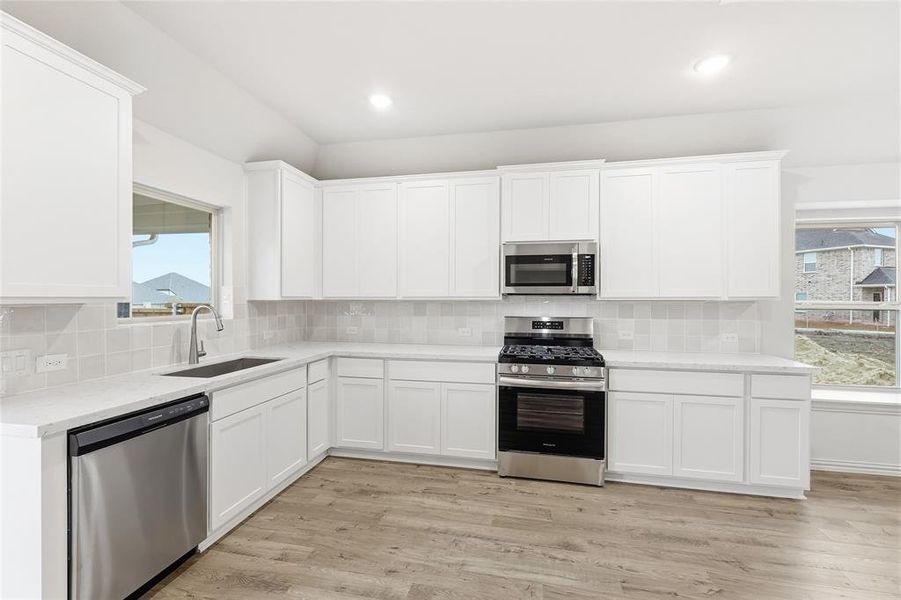 Kitchen with appliances with stainless steel finishes, healthy amount of natural light, decorative backsplash, and recessed lighting