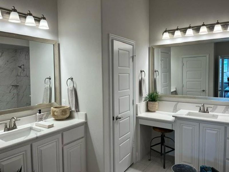 Bathroom featuring two vanities, a marble finish shower, and light tile patterned floors Bathroom featuring two vanities, a marble finish shower, and light tile patterned floors