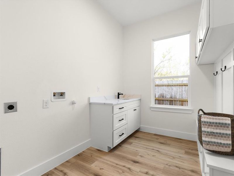 Laundry room featuring light wood finished floors, hookup for a washing machine, cabinet space, and electric dryer hookup