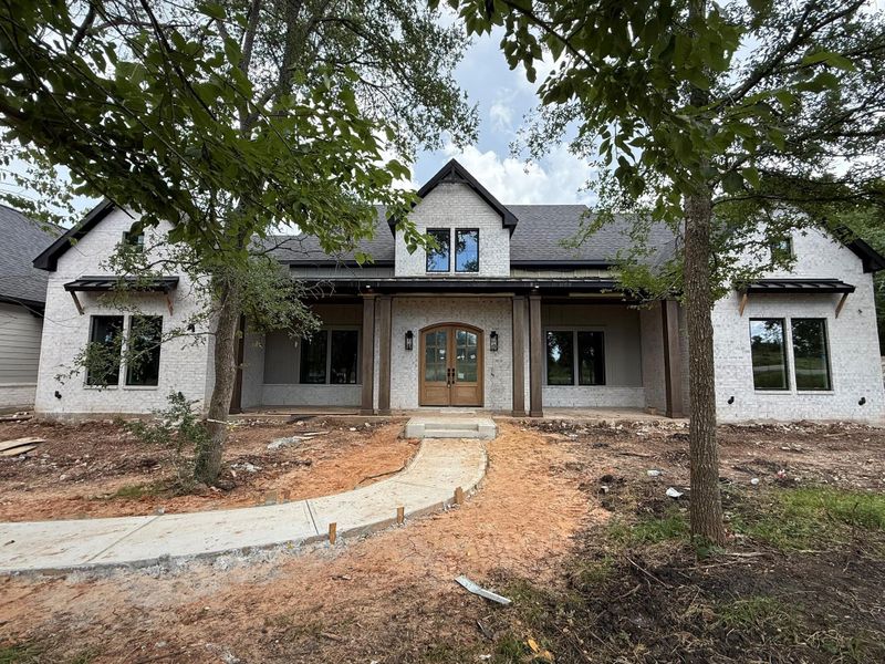 View of front of house featuring french doors, a shingled roof, and brick siding