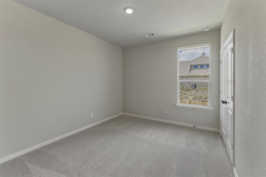 Neutral-toned interior room featuring light gray carpeting, white baseboards, and a single window with white trim Neutral-toned interior room featuring light gray carpeting, white baseboards, and a single window with white trim