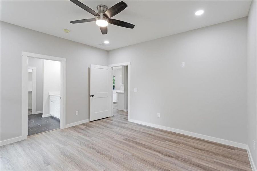 Unfurnished bedroom featuring ensuite bath, light hardwood / wood-style flooring, and ceiling fan