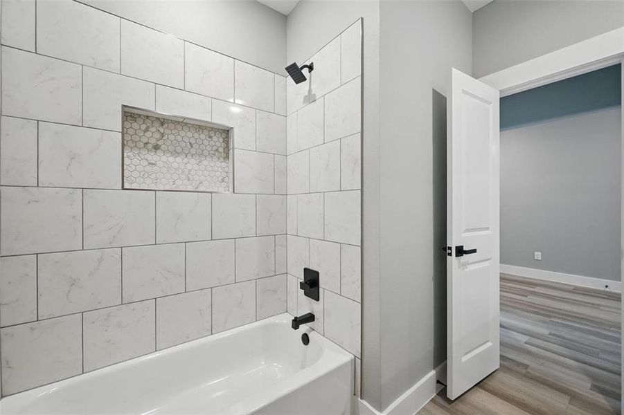 Full bathroom featuring  shower combination, wood finished floors, and baseboards