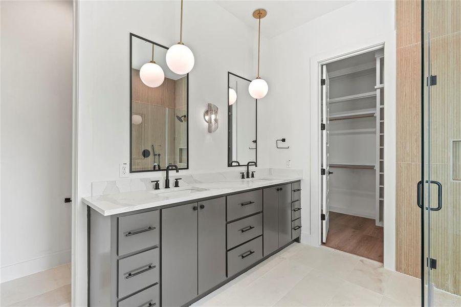 Full bathroom with a shower stall, a spacious closet, double vanity, and light tile patterned floors Full bathroom with a shower stall, a spacious closet, double vanity, and light tile patterned floors