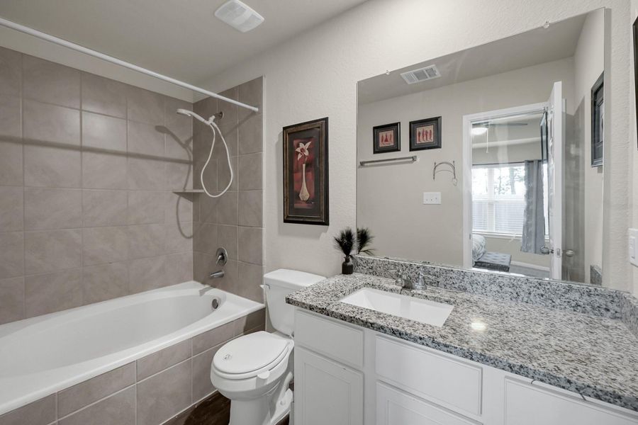 Primary bath features granite countertops and a soaking tub with tile surround.