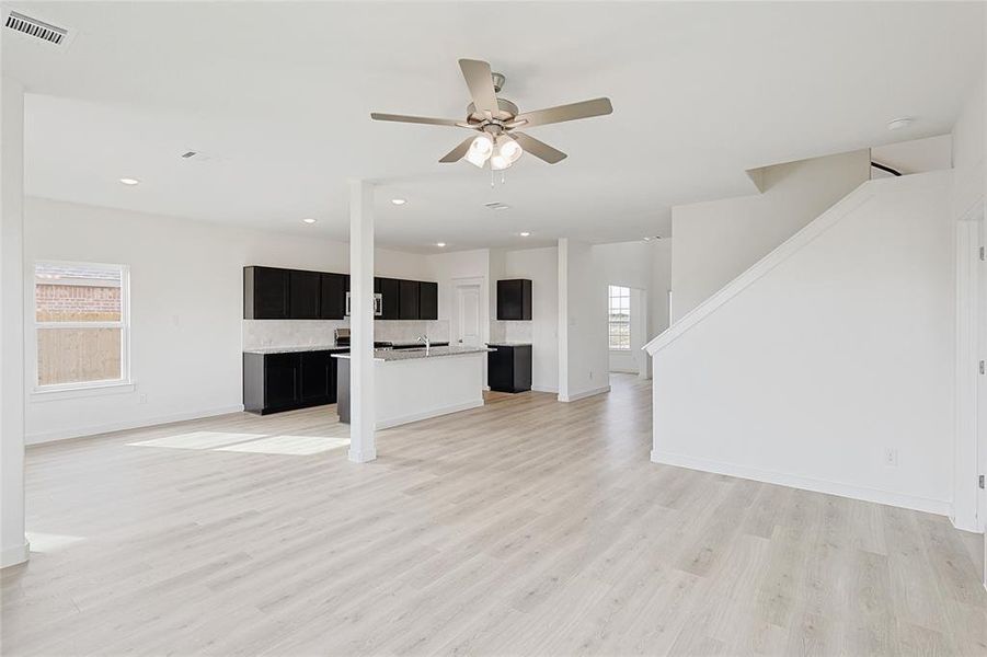 Unfurnished living room featuring ceiling fan and light wood-type flooring