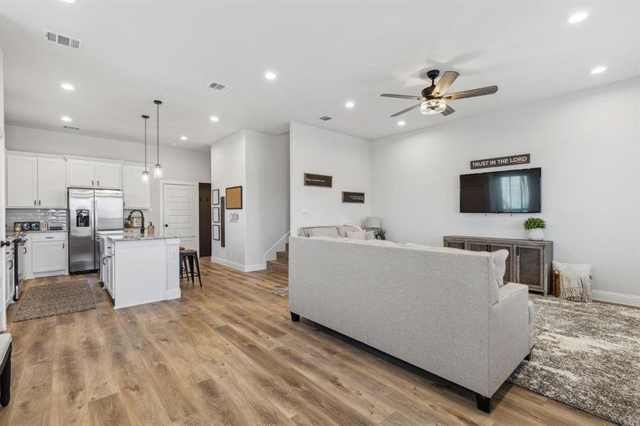 Living room with ceiling fan and light hardwood / wood-style floors